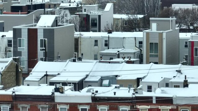 Row houses in American city with snow. Aerial tilt up zoom lens revealing large city skyline with snowy clouds.
