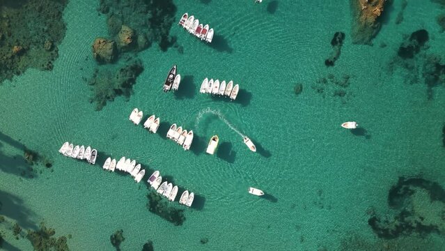 Bird's eye view of turquoise green crystal clear ocean water with small boats anchored in Corfu Greece