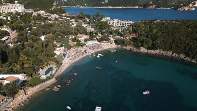High angle bird's eye view above coastal bay of Corfu Greece with rows of beach umbrellas from hotel