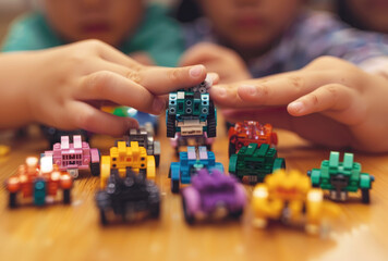 Children's hands build LEGO robots and small structures on the table in a closeup of children...