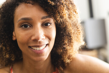 A biracial woman with curly hair smiles warmly at the camera - Powered by Adobe