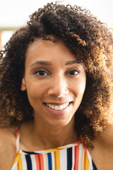 Biracial woman with curly hair smiles warmly, her eyes gleaming with joy