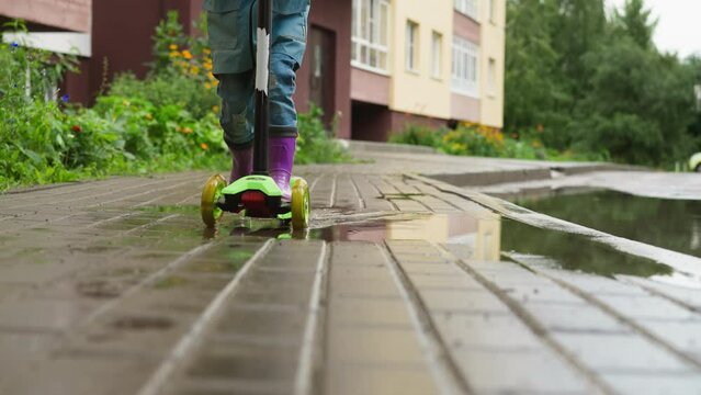 Kid scooter cuts through rain-soaked air. Child on scooter embraces spontaneity of moment finding beauty and wonder in simplicity of rainy day ride