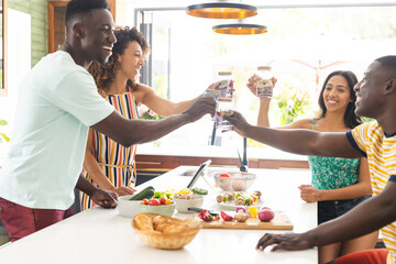 Diverse group of friends toast in a bright kitchen setting