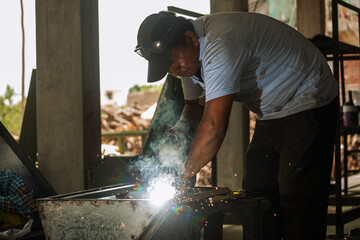 Latino man welding machine in the field