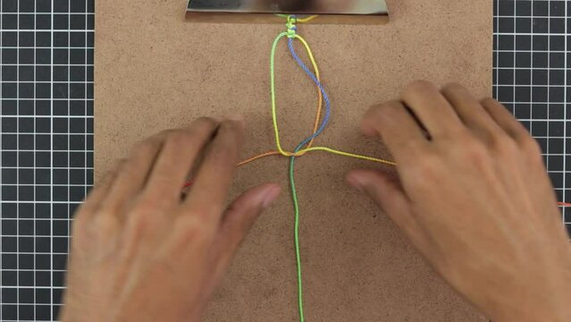 Timelapse of hands crafting colorful rainbow macrame bracelet, vibrant threads