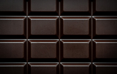 Close up macro of squares of a bar of dark chocolate from above.