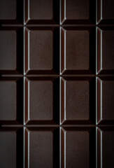 Close up macro of squares of a bar of dark chocolate from above.