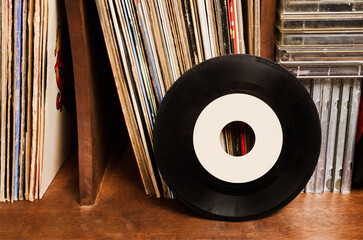 Vinyl records stacked with cassettes on furniture.