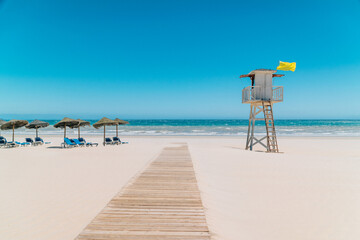 Sunny Beach Day with Lifeguard Tower and Umbrellas