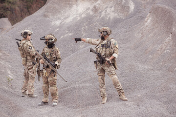 Soldiers in camouflage military uniforms carrying weapons, Reconnaissance missions in rugged...