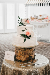 white wedding cake with big flowers on rustic stand