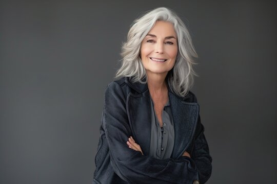 A woman with gray hair is wearing a black jacket and smiling