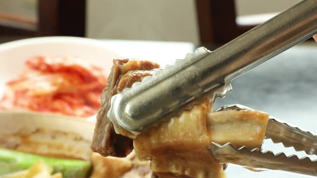 전골냄비에서 보글보글 끓고있는 부드러운 갈비찜의 살코기와 뼈를 분리하는 모습