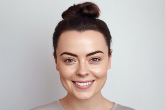 Young beautiful brunette woman with short hair and toothy smile on white background, looking at camera, close up portrait.