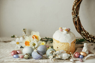 Fototapeta na wymiar Happy Easter! Stylish easter eggs, cake, bunnies, cherry blossom and daffodils on rustic table. Modern natural dyed eggs, holiday food and spring flowers. Easter countryside still life