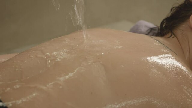 Relaxing spa treatments. Young girl having back massage in spa hotel. Water