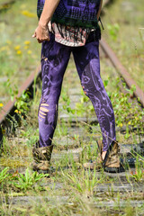 Woman legs in colorful and cut out leggings, walking on railway