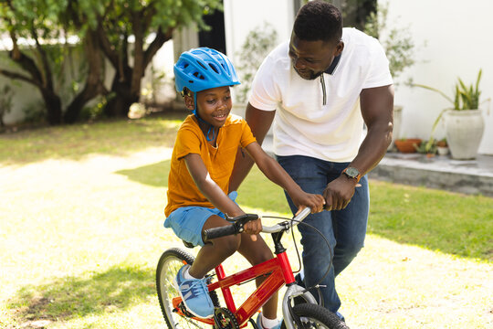 Father teaches his son to ride a bike in a sunny backyard