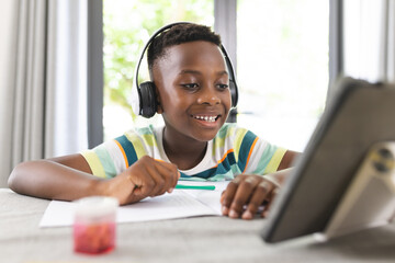 African American boy with headphones uses a tablet for online learning