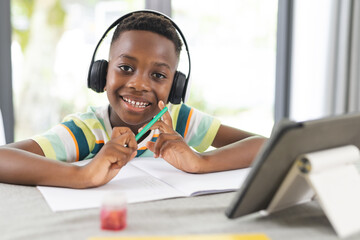 African American boy with headphones studies online at a tablet