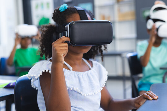 Biracial girl with curly hair explores virtual reality in school, classmates in background