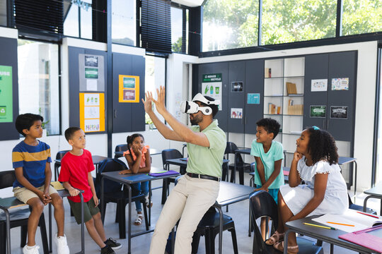 Young Asian male teacher is teaching a diverse group of children in a classroom setting in school