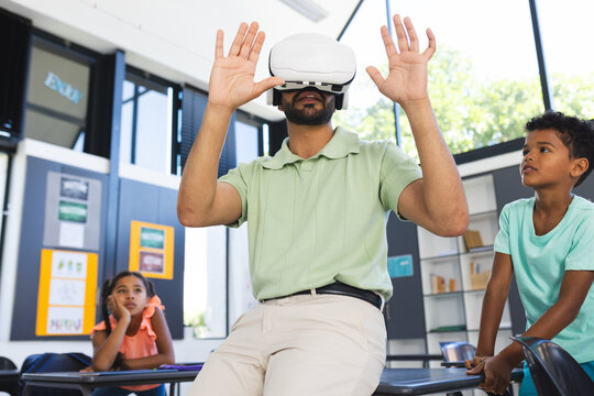 Young Asian male teacher explores virtual reality, wearing a VR headset in a classroom in school