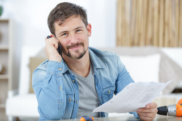 male diy expert using smartphone and holding instructions