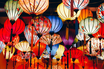 A colorful array of traditional paper lanterns, illuminated and suspended, creates a festive...