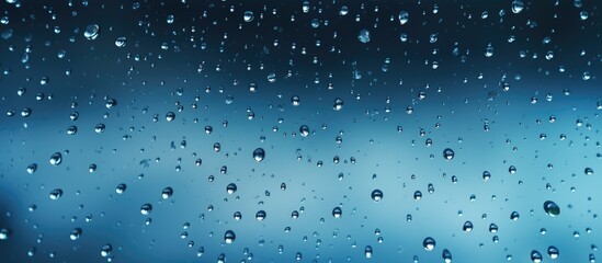Multiple water drops cling to a window against a backdrop of electric blue, showcasing the beauty of moisture and fluidity in nature