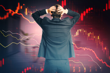 Back view of stressed young european businessman with abstract downward red forex chart on blurry...