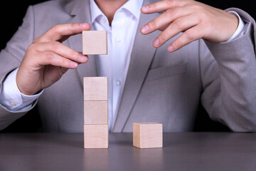 A businessman builds a pyramid of wooden cubes to write a five-letter word. Copy space