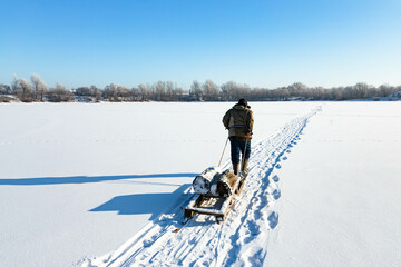 A lonely old hermit, in winter, crosses the river on ice and pulls a sled with firewood for heating