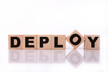 DEPLOY word, text written on wooden cubes on a white background with reflection.