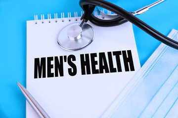 Men's Health, text written in a notebook lying on a blue background, with a stethoscope and a...