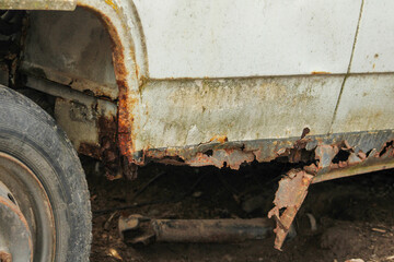 The rusty sills of an old abandoned car.