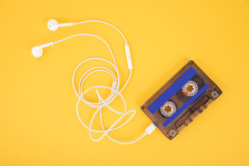 Tape cassette and white headphones. Composition in the form of a player on a yellow background.