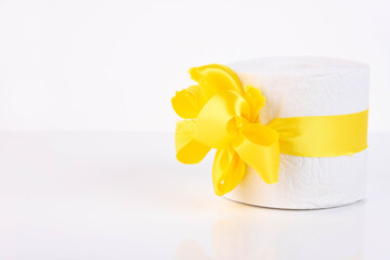 White perforated roll of soft toilet paper with a bright orange bow, as on a present. White background. Copy space