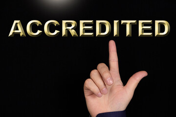 ACCREDITED text, a word written on a black background pointed to by a hand with the index finger of a person.