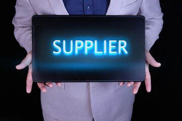 SUPPLIER word, text written in neon letters on a laptop which is being held by a businessman in a...