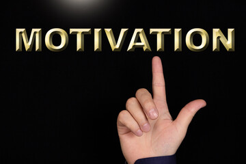 MOTIVATION text, a word written on a black background pointed to by a hand with the index finger of a person.