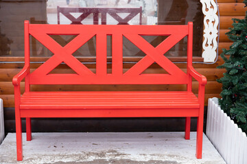 Red, empty wooden bench outside in winter.