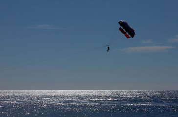 Tourists fly over the sea and the beach on a parachute