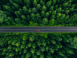 Aerial view of car with a roof rack on a country road and green woods in Finland