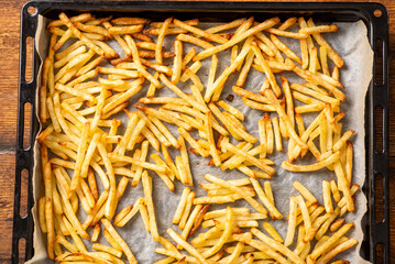 fried french fries lying on baking paper. Cooking frozen French fries in the oven