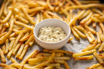 Close-up of white sauce with greens and freshly cooked golden fries lying next to it