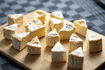 Camembert cheese cut into triangles on a wooden cutting board on a dark background