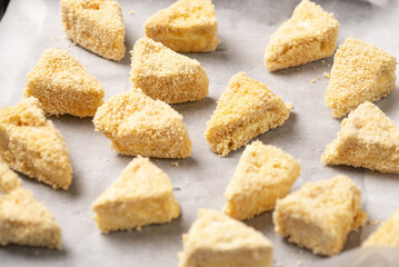 Slices of Camembert cheese wrapped in breadcrumbs on baking paper