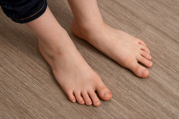 Innocent bare feet of a child rest on the ground, portraying the simplicity and purity of early...